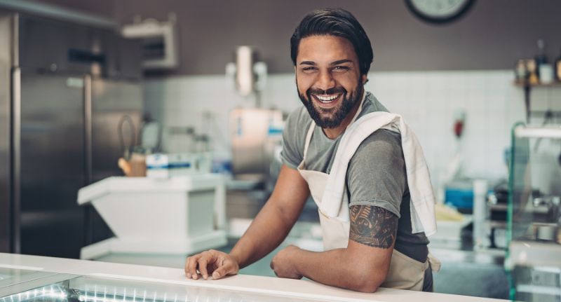 Empreendedor sorrindo em sua pequena empresa no ramo de alimentação